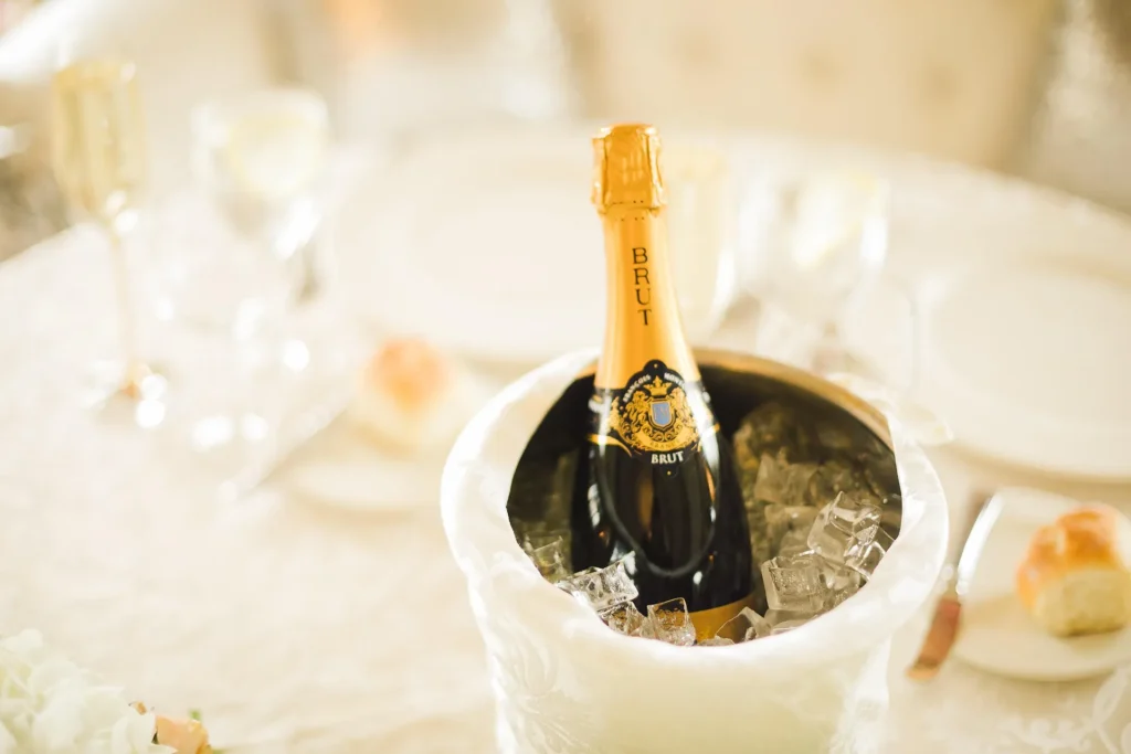 Brut champagne bottle chilling in an ice bucket on an elegantly set dining table with glasses in soft bokeh light