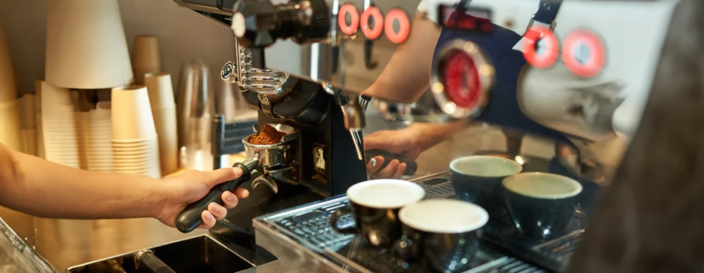 Professional espresso machine brewing multiple shots simultaneously into glass cups with warm golden ambient lighting, close-up view