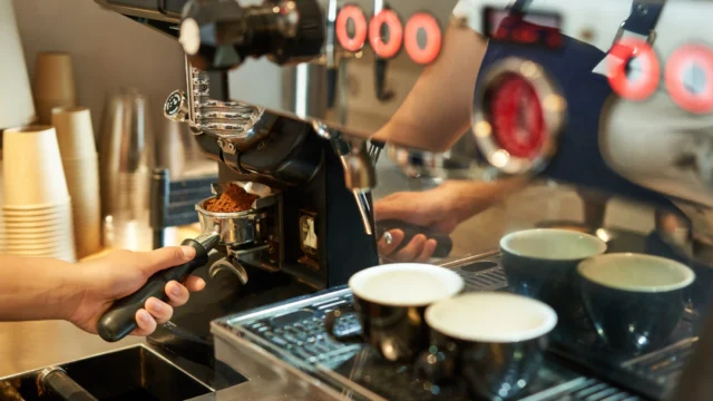 Professional espresso machine brewing multiple shots simultaneously into glass cups with warm golden ambient lighting, close-up view