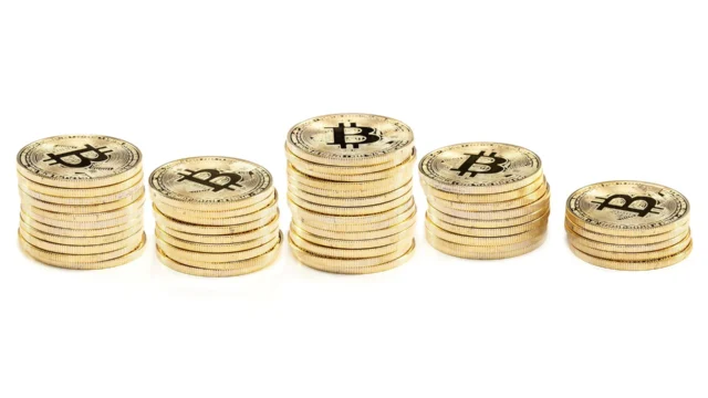 Five stacks of gold Bitcoin coins of varying heights arranged in a row on a white background